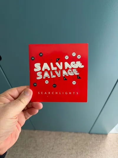 Salvage《Searchlights》CD 单曲的外封套，红底白字印着乐队名与曲目
